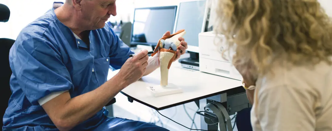 ortopeden visar ett korsband på en modell för en patienten